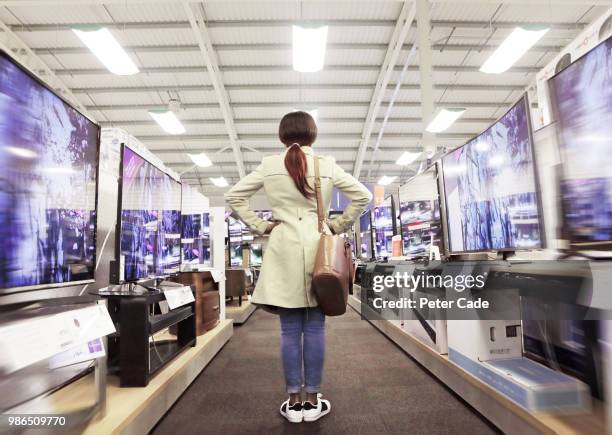 young woman in shop looking at televisions - smart tv fotografías e imágenes de stock