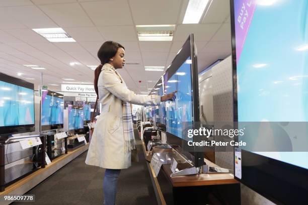 young woman in shop looking at televisions - retailer shopping customer tv stockfoto's en -beelden