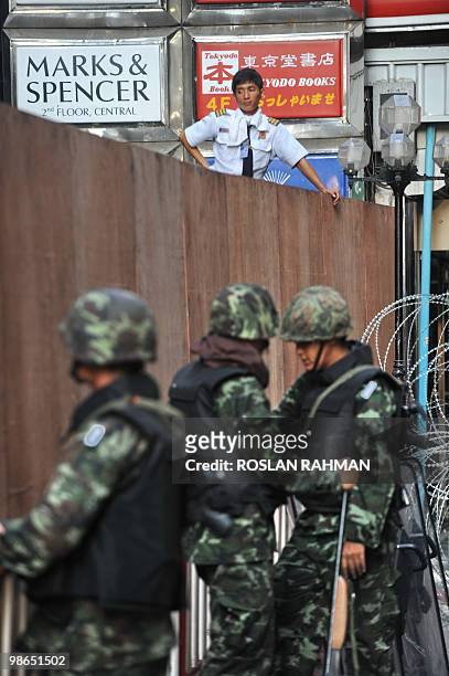 Security guard looks out from a plywood fence while Thai soldiers stand aloog the street off Silom Road in the financial district of central Bangkok...