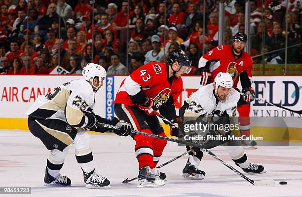 Peter Regin of the Ottawa Senators gets checked by Maxime Talbot and Craig Adams of the Pittsburgh Penguins as he tries to carry the puck over the...