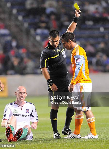 Referee Ricardo Salazar gives a yellow card to Danny Cruz of the Houston Dynamo's as Tim Ward of the Fire sits on the ground in an MLS match on April...