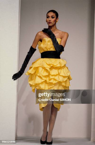 Robe bustier à volants portée avec de longs gants noirs au défilé Balmain Haute Couture Printemps-Eté le 28 janvier 1985 à Paris, France.