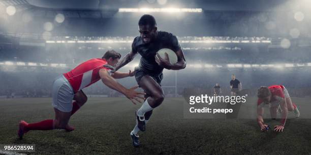 pro rugby player running with ball past tackling opponent - tackling stock pictures, royalty-free photos & images