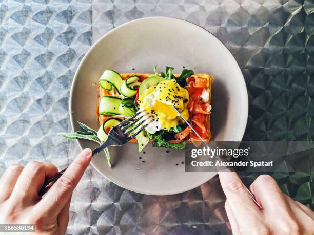 eating brunch with waffle, avocado, cucumber, salmon and poached egg, personal perspective - 豪華　食事 ストックフォトと画像