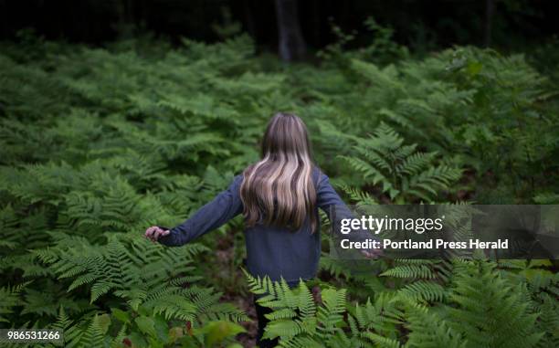 Rhys Cote walks through a patch of ferns while playing in the backyard at her home in Wells. Rhys has been modeling since she was a toddler and has...