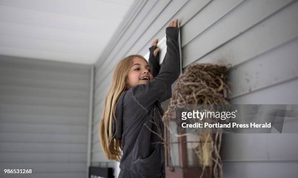 Rhys Cote is lifted up by her mom, Tina Cote, to peek inside of a birds nest on their porch at their home in Wells. Rhys has been modeling since she...