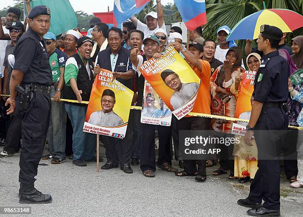 Supporters of the opposition coalition chant slogans outside a polling centre during the Hulu Selangor parliamentary by-election in Hulu Selangor on...