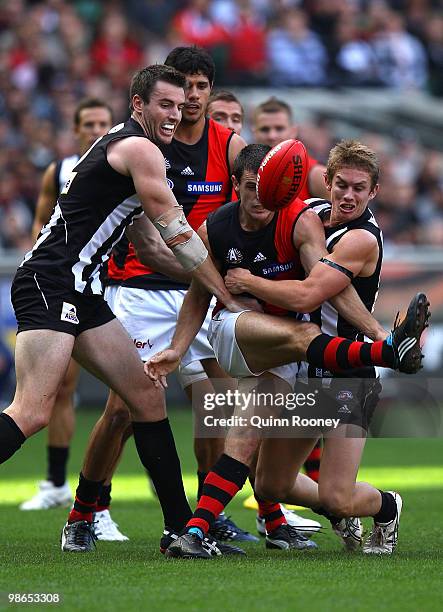 Brent Stanton of the Bombers kicks whilst being tackled during the round five AFL match between the Collingwood Magpies and the Essendon Bombers at...