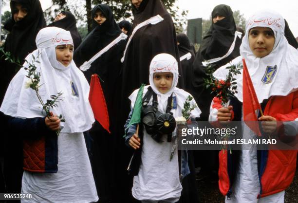 Femmes et enfants tenant des rameaux, symbole de paix, participant à la manifestation des Bassidjis, miliciens pro-Khomeiny, le 1er décembre 1986 à...