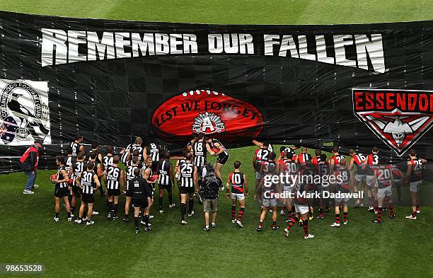 Collingwood and Essendon players run through the Anzac Day banner during the round five AFL match between the Collingwood Magpies and the Essendon...