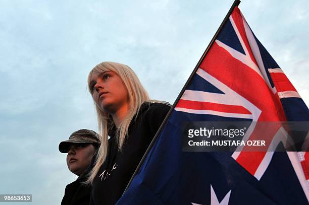 Australians sit next to their national flag as they attend a ceremony commemorating Anzac Day, at Anzac Cove, in western Canakkale on April 25, 2010....