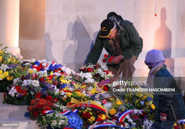 Man and a young girl place flowers at the foot of a memorial wall during a dawn service commemorating Anzac Day on the WWI battlefield of...