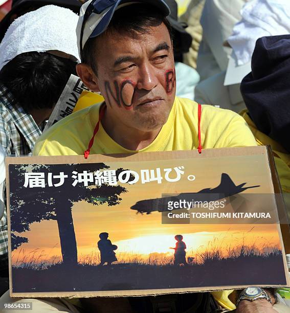 Protester holds a picture with a message "Reach the Voice of Okinawa" during a rally against the continued US airbase presence on the island, at...