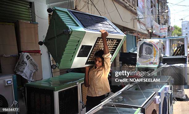 An Indian worker carries an air cooler to a customer's vehicle in Hyderabad on April 25, 2010. Air coolers are in high demand during the summer...