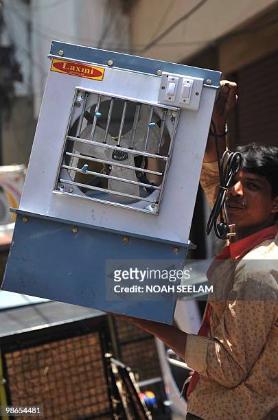 An Indian worker carries an air cooler to a customer's vehicle in Hyderabad on April 25, 2010. Air coolers are in high demand during the summer...