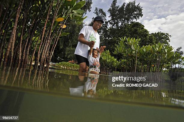 This photo taken on April 24, 2010 shows "Surio" takes his three-year-old daughter Nesa to a mangrove plantation area at the Thousand Islands...