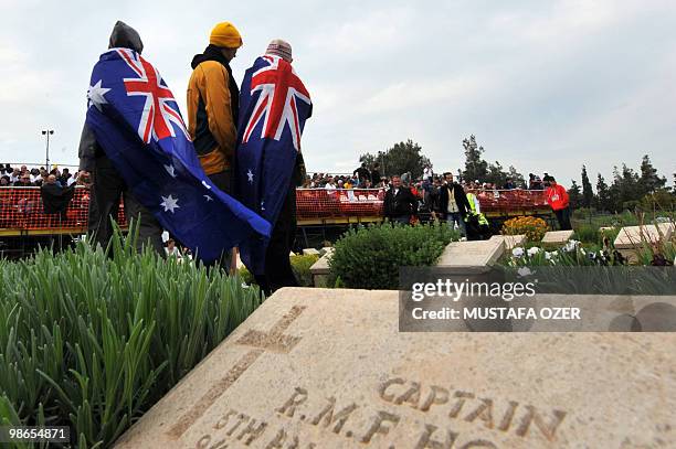 Australians stand by the grave of an Australian soldier during a ceremony commemorating Anzac Day, at Anzac Cove, in western Canakkale on April 25,...