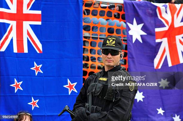 Turkish army special forces member stands in front of an Australian and a New Zealand flag during a ceremony commemorating Anzac Day, at Anzac Cove,...
