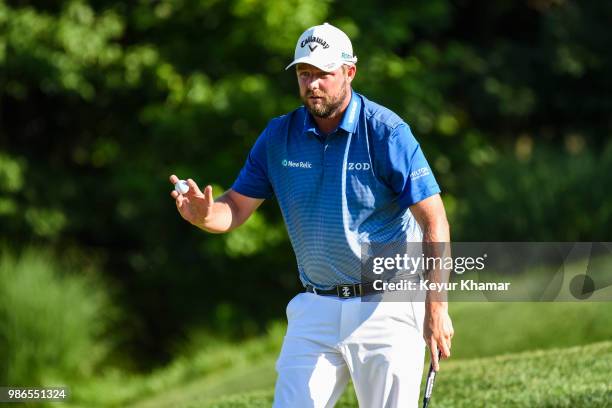 Marc Leishman of Australia waves his ball to fans after making a birdie putt on the 18th hole green during the first round of the Quicken Loans...