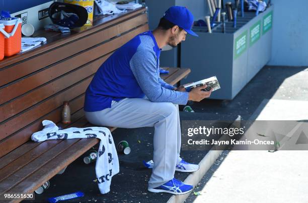 Yu Darvish of the Chicago Cubs looks over the team media guide as he sits in the dugout during the game against the Los Angeles Dodgers at Dodger...