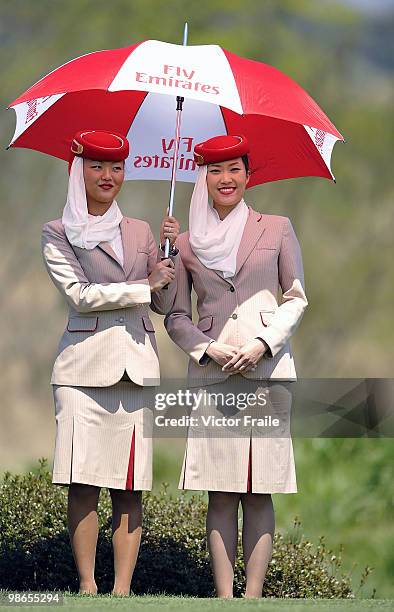 Fly Emirates' hostesses hold umbrellas on the 14th hole during the Round Three of the Ballantine's Championship at Pinx Golf Club on April 25, 2010...