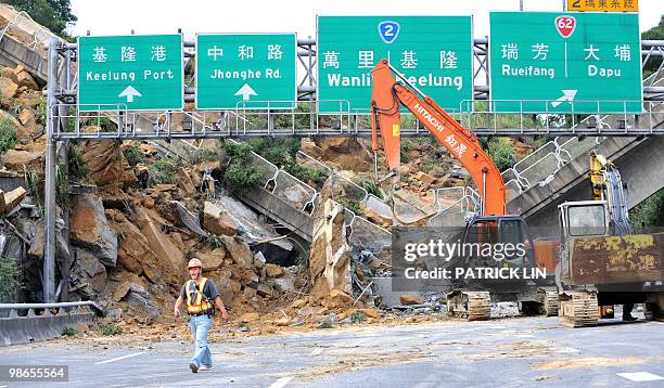 Rescuer inspects the damage next to a collapsed bridge and rubble blocking a freeway near Taiwan's northern Keelung port on April 25, 2010 following...