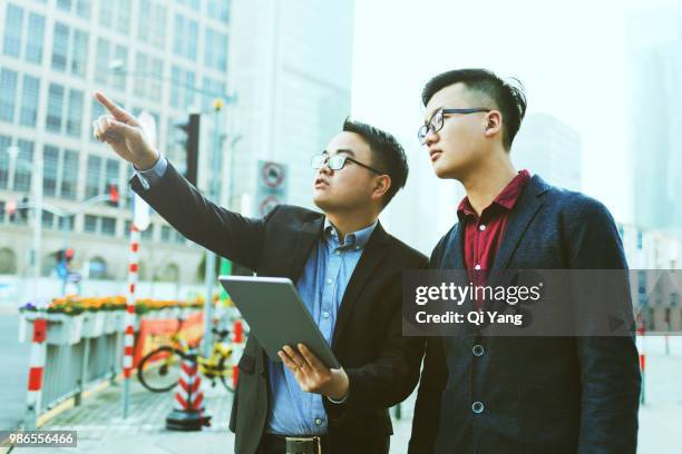 two businessmen talking outdoors - qi yang stock pictures, royalty-free photos & images