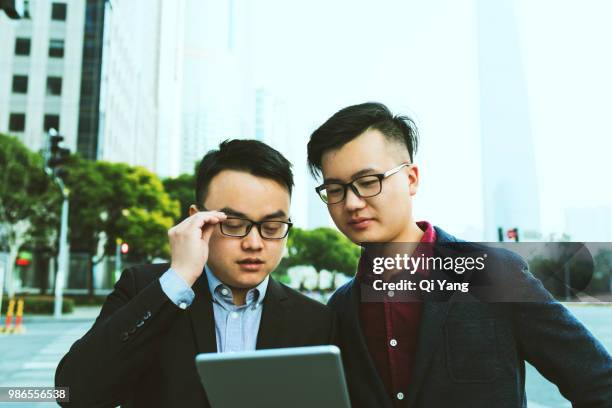 two businessmen talking outdoors - qi yang stock pictures, royalty-free photos & images