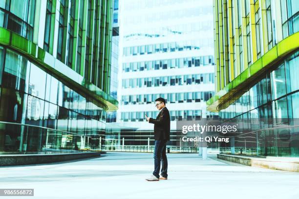 businessman looking at smartphone - qi yang stock pictures, royalty-free photos & images