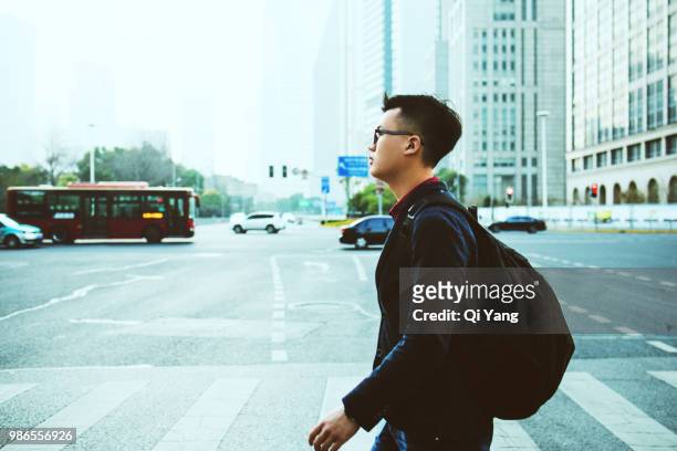 businessman crossing the road - qi yang stock pictures, royalty-free photos & images