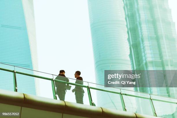 two businessmen standing on bridge and talking - international day two fotografías e imágenes de stock