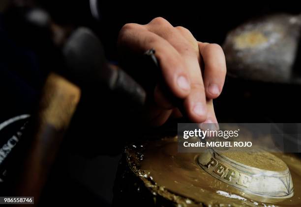 Craftman engraves a gold and silver ferrule for a mate at the workshop of traditional handmade silverware store "Bresciani" in Montevideo on June 27,...