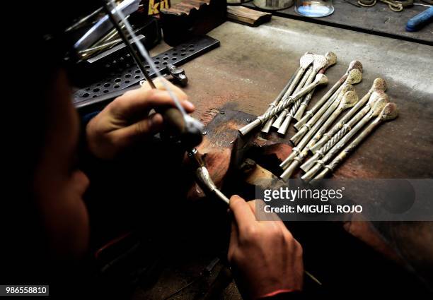 Craftman works on a gold and silver "bombilla" at the workshop of traditional handmade silverware store "Bresciani" in Montevideo on June 27, 2018. -...