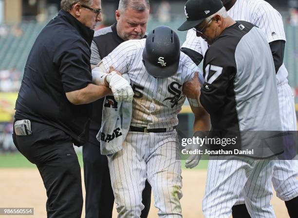 Yolmer Sanchez of the Chicago White Sox is helped up by trainer Herm Schneider and manager Rick Renteria after suffering a leg injury at first base...