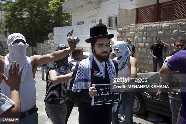 Member of Neturei Karta , a fringe of ultra-Orthodox movement within the anti-Zionist bloc in Israel, stands amid masked Palestinian youths during...