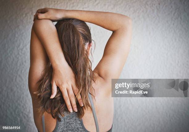 young woman doing arm stretches as pre-exercise warm-up - girl in tank top stock pictures, royalty-free photos & images