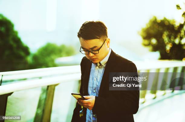 businessman holding smartphone walking on the bridge - qi yang stock pictures, royalty-free photos & images