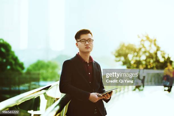 businessman holding digital tablet on the bridge - qi yang stock pictures, royalty-free photos & images