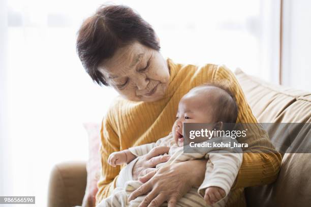 grandmother taking care of baby girl - asian grandmother stock pictures, royalty-free photos & images