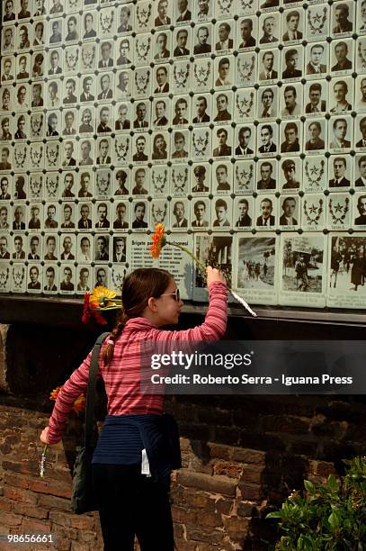 Youing woman lays a flower as she looks at pictures of Italian insurgents killed during World War II on the wall of the Resistenza's shrine at...