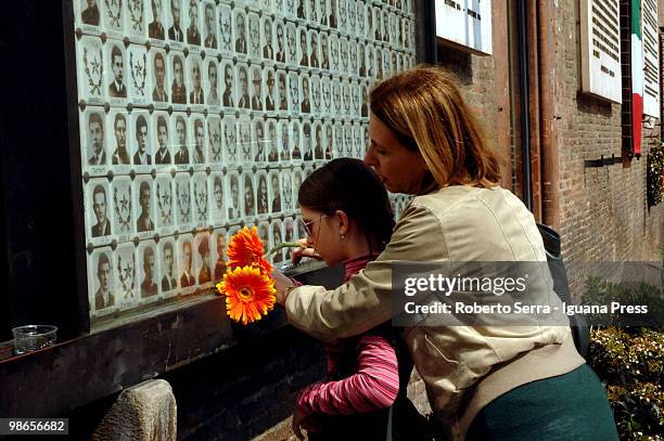 Woman lays flowers as she looks at pictures of Italian insurgents killed during World War II on the wall of the Resistenza's shrine at Neptune square...