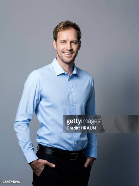 smiling businessman standing with hands in pockets - man white studio shot collared shirt stock pictures, royalty-free photos & images