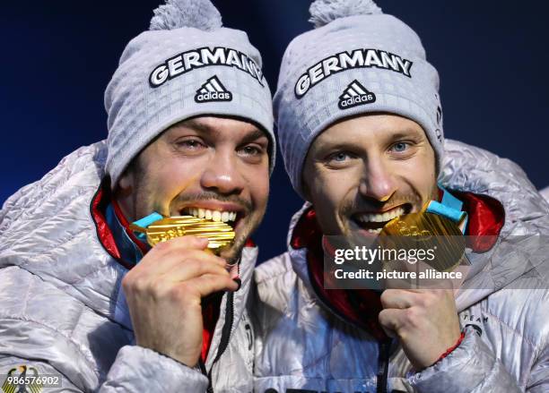 Tobias Wendl and Tobias Arlt from Germany biting their gold medals during the award ceremony of the team luge event of the 2018 Winter Olympics in...