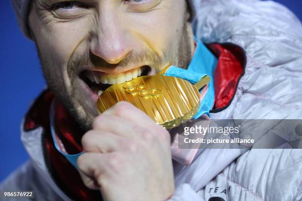 Tobias Arlt from Germany biting his gold medal during the award ceremony of the team luge event of the 2018 Winter Olympics in Pyeongchang, South...