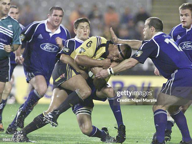 Jerry Collins of the Hurricanes is tackled by James Arlidge and Craig Innes of the Blues during the Super 12 match between the Blues and the...