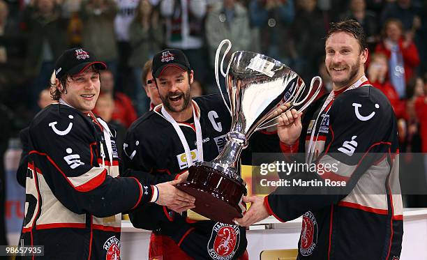 Patrick Koeppchen, Tino Boos and Sascha Goc of Hannover celebrate with the trophy after winning the DEL play off final match between Hannover...