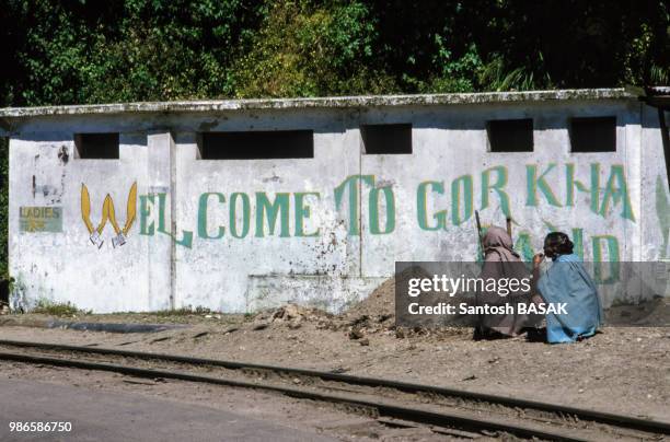 Femme assises le long d'un mur à Darjeeling le 15 novembre 1986, Inde.