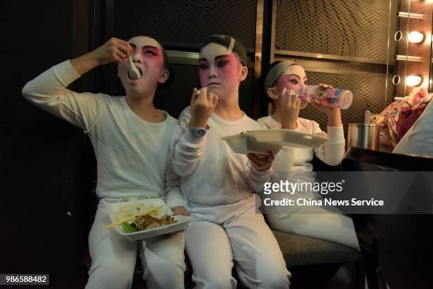 Schoolchildren eat food as they prepare backstage prior to a Cantonese opera performance on June 26, 2018 in Hong Kong, China. Thirty-four children...