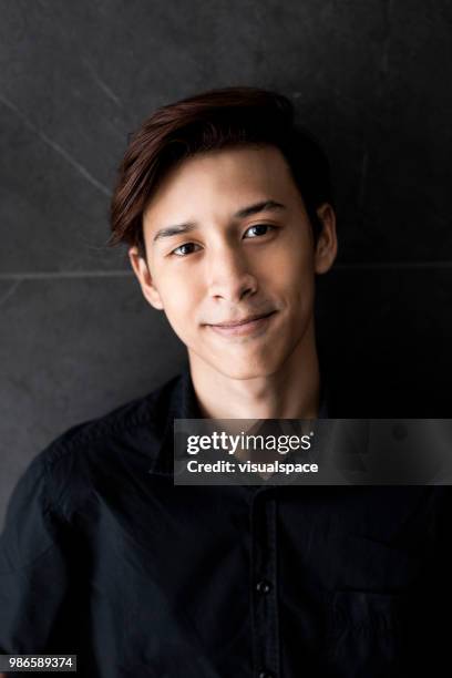 young boy standing against a grey wall. - malaysian people stock pictures, royalty-free photos & images