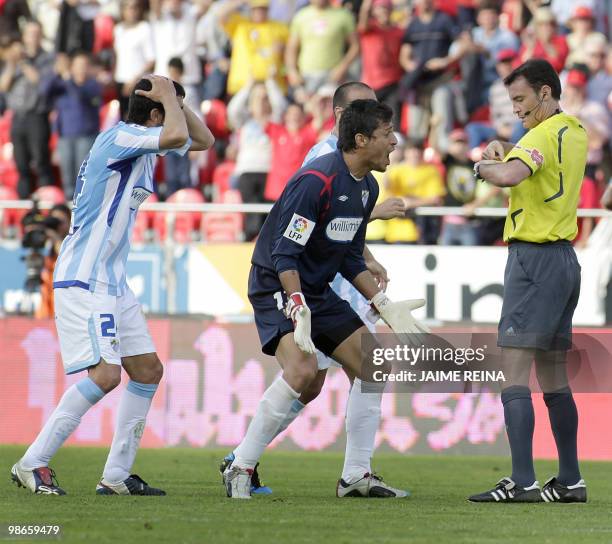 Malaga's Uruguayan goalkeeper Gustavo Munua reacts next to referee Mejuto Gonzalez during their Spanish League football match at the Ono Stadium in...